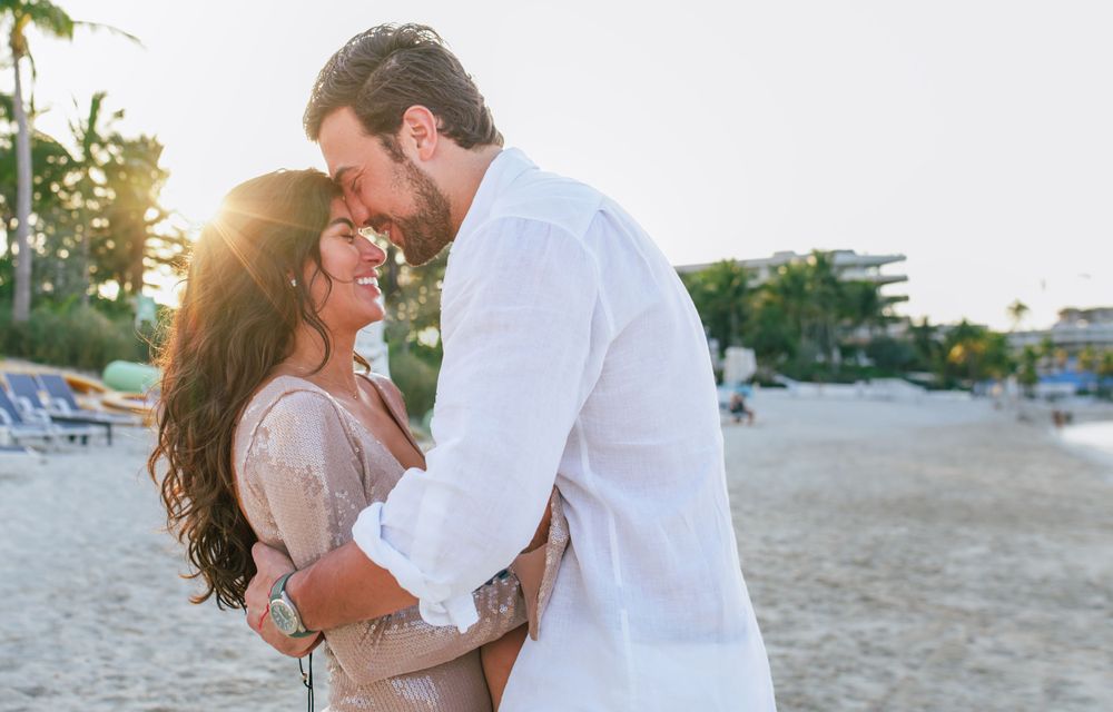 Romantic couple embracing on beach during golden hour sunset.