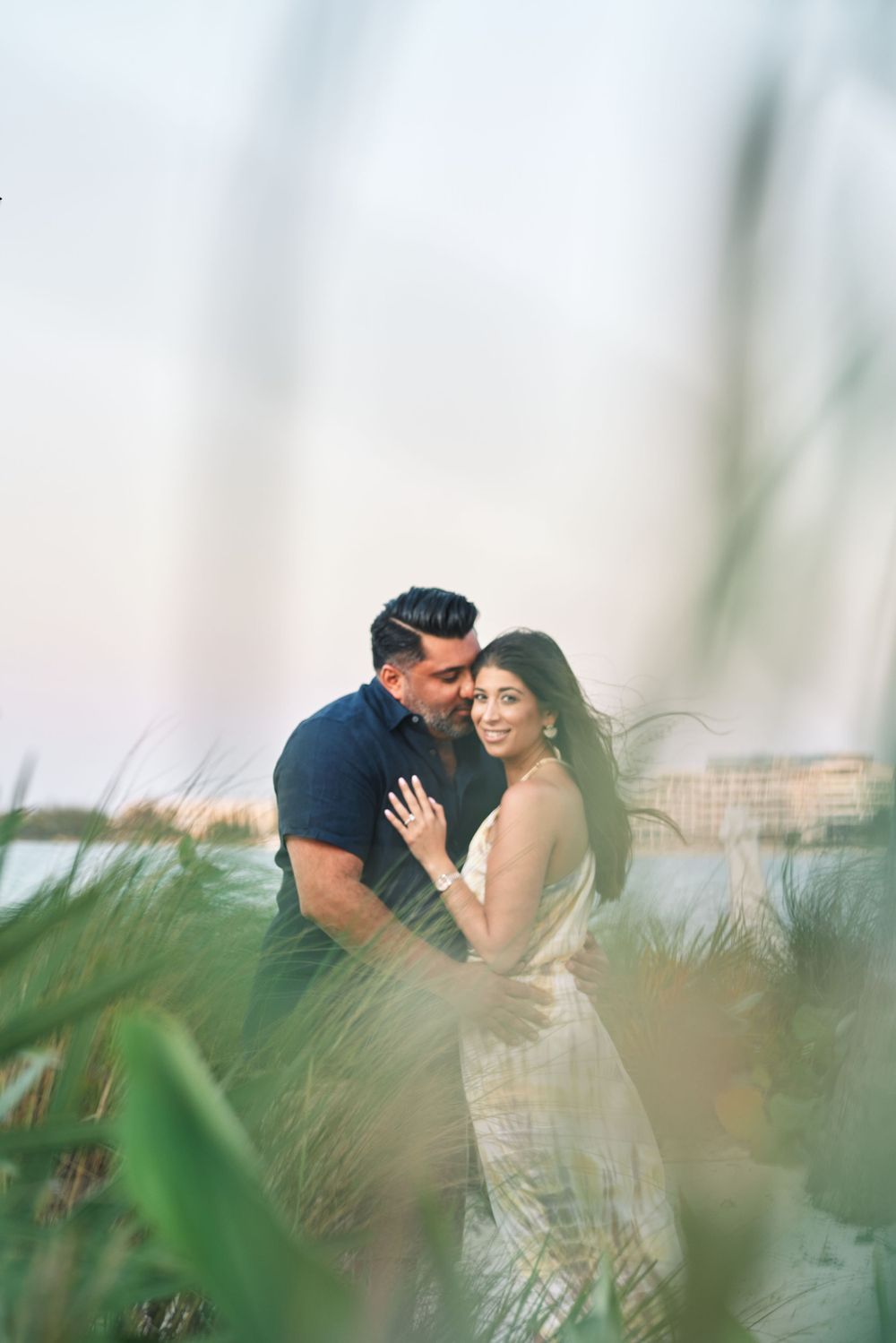Romantic couple embracing in tall grass with soft dreamy background.