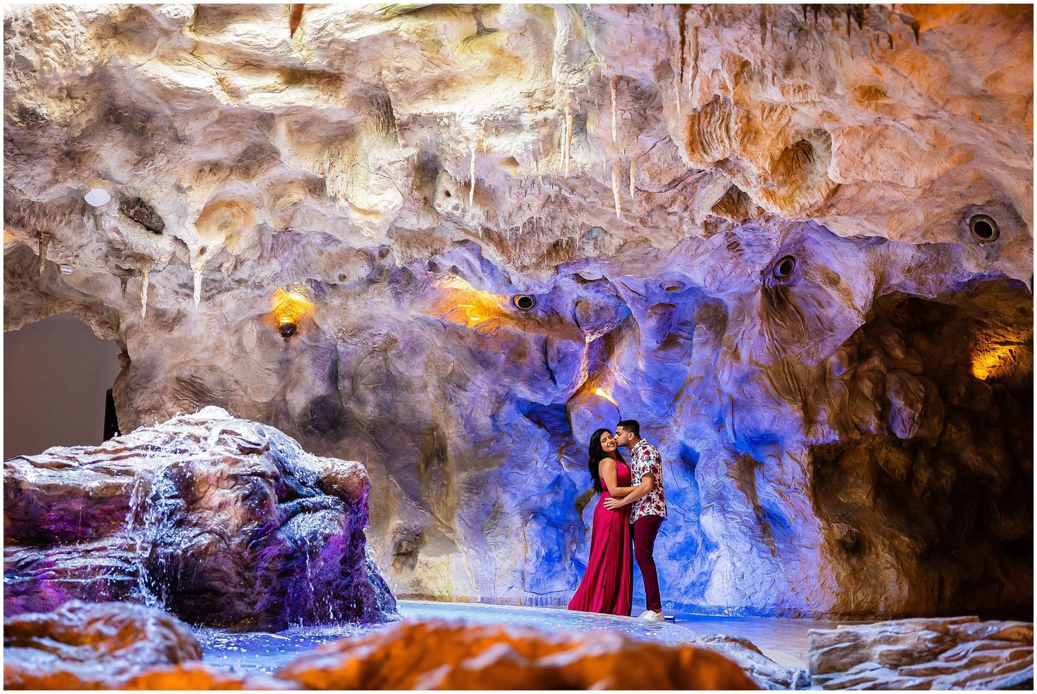 Dramatic cave photoshoot with purple lighting and natural rock formations.