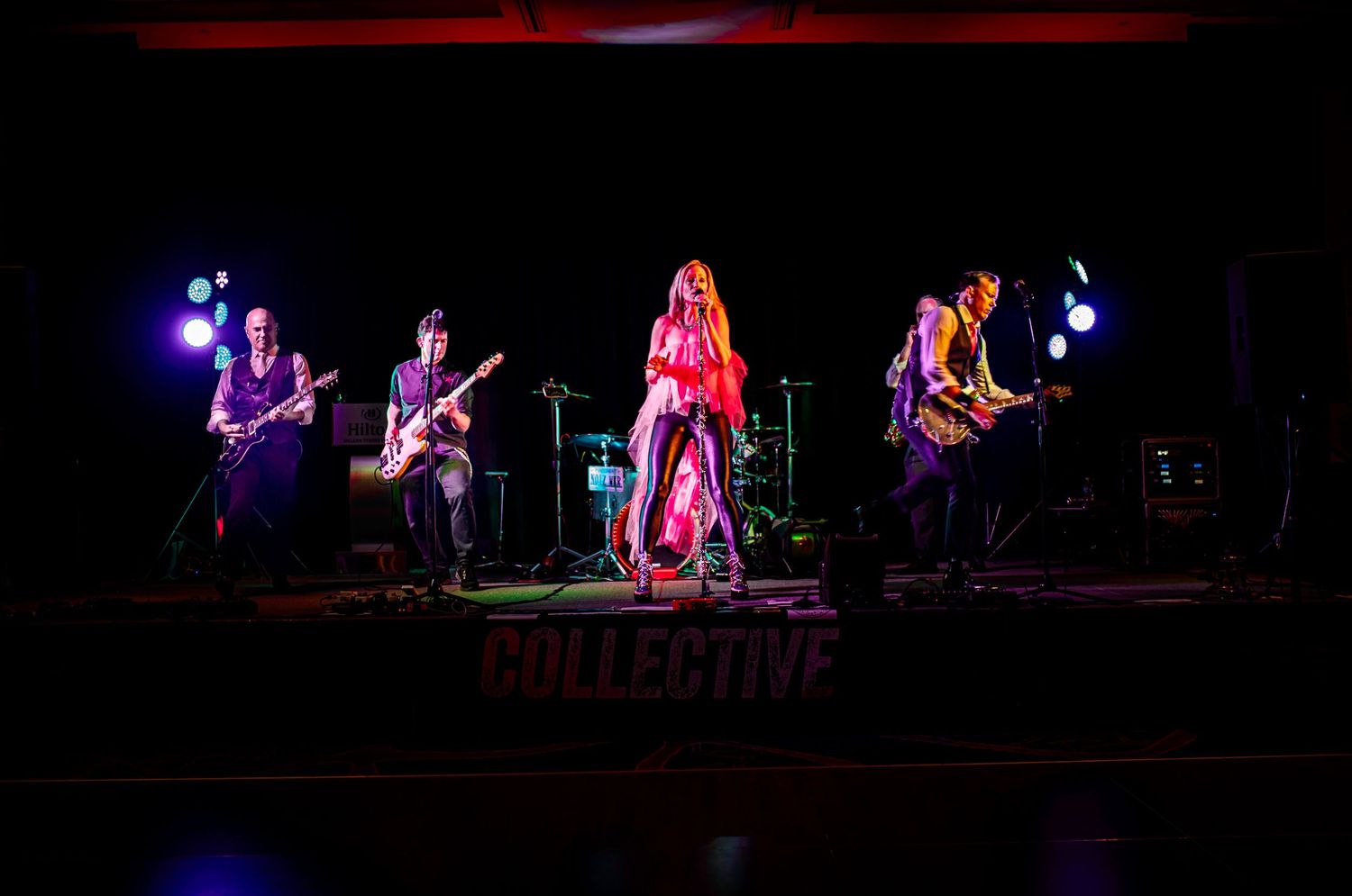 Rock band performing on stage with dramatic red and purple lighting effects.