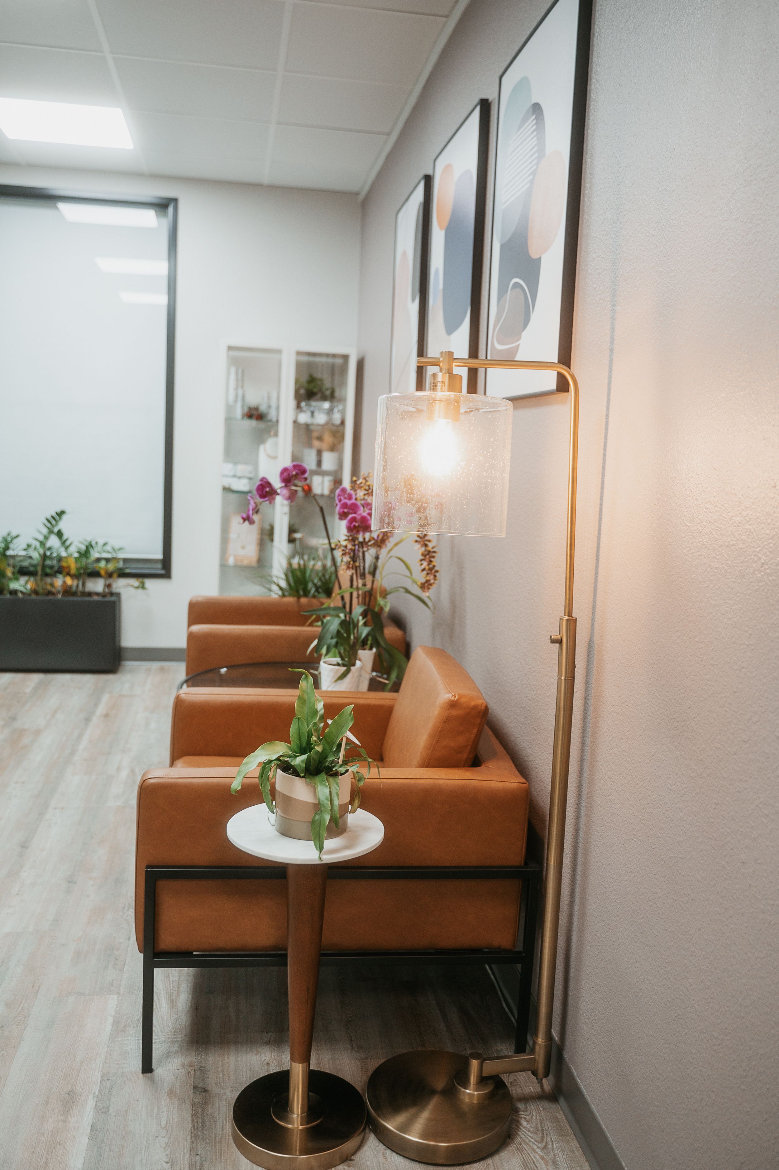 Modern waiting area with brown leather chairs and decorative orchids on side tables.