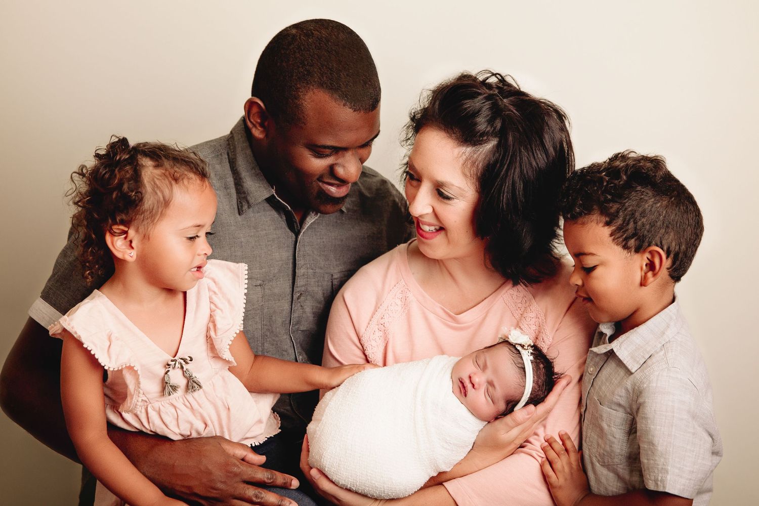 family of 5 mom dad and siblings admire newborn baby girl
