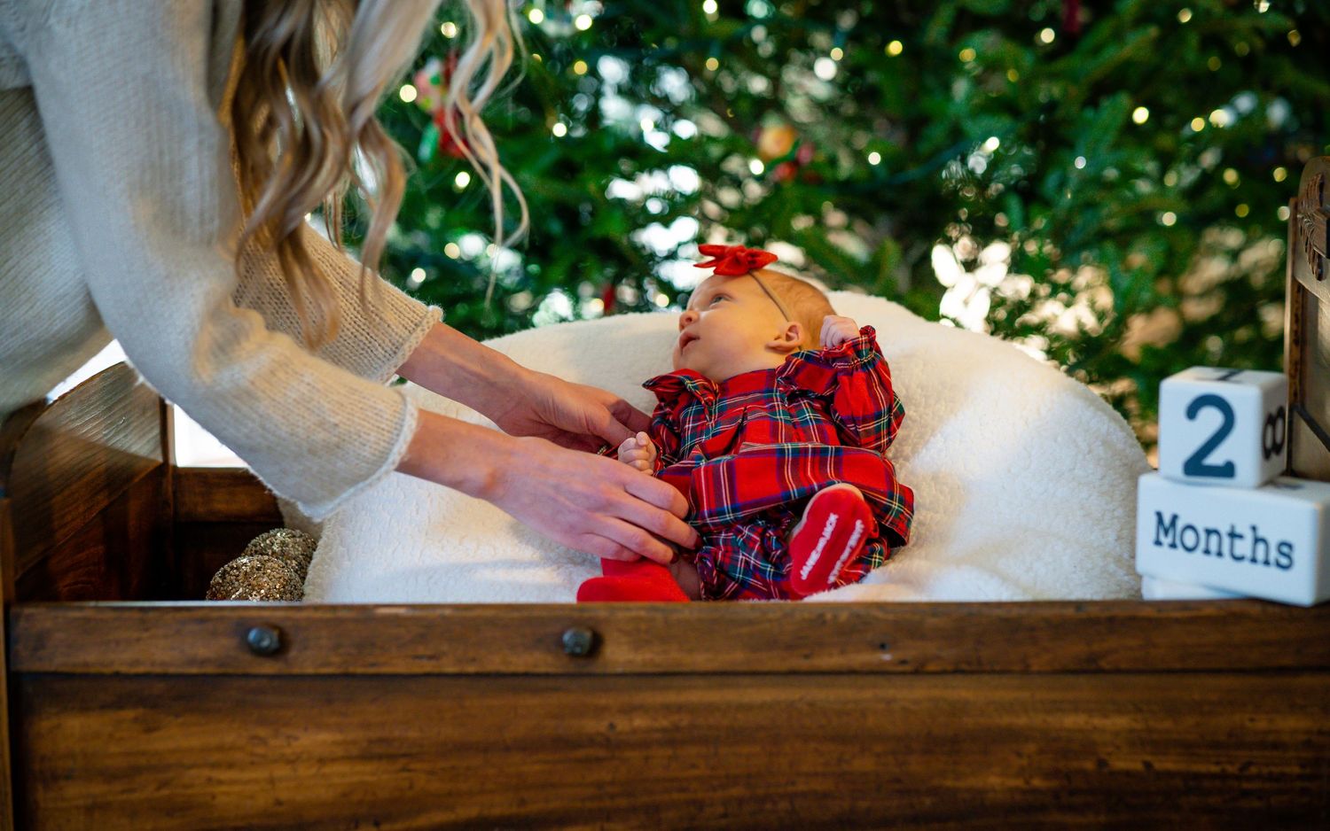 A tiny plaid outfit laid out on a rustic wooden surface with milestone markers.