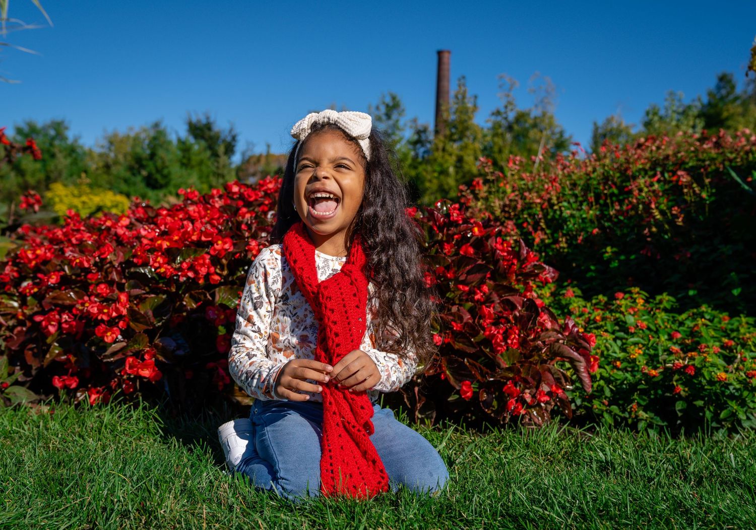 A joyful moment captured against vibrant red flowers in a sunny garden.
