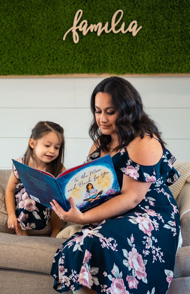 Reading a storybook together on a couch with a 'family' sign on the wall.