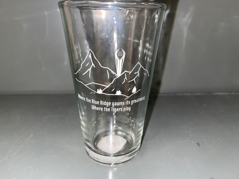 Clear glass pint with etched mountain landscape design and text.