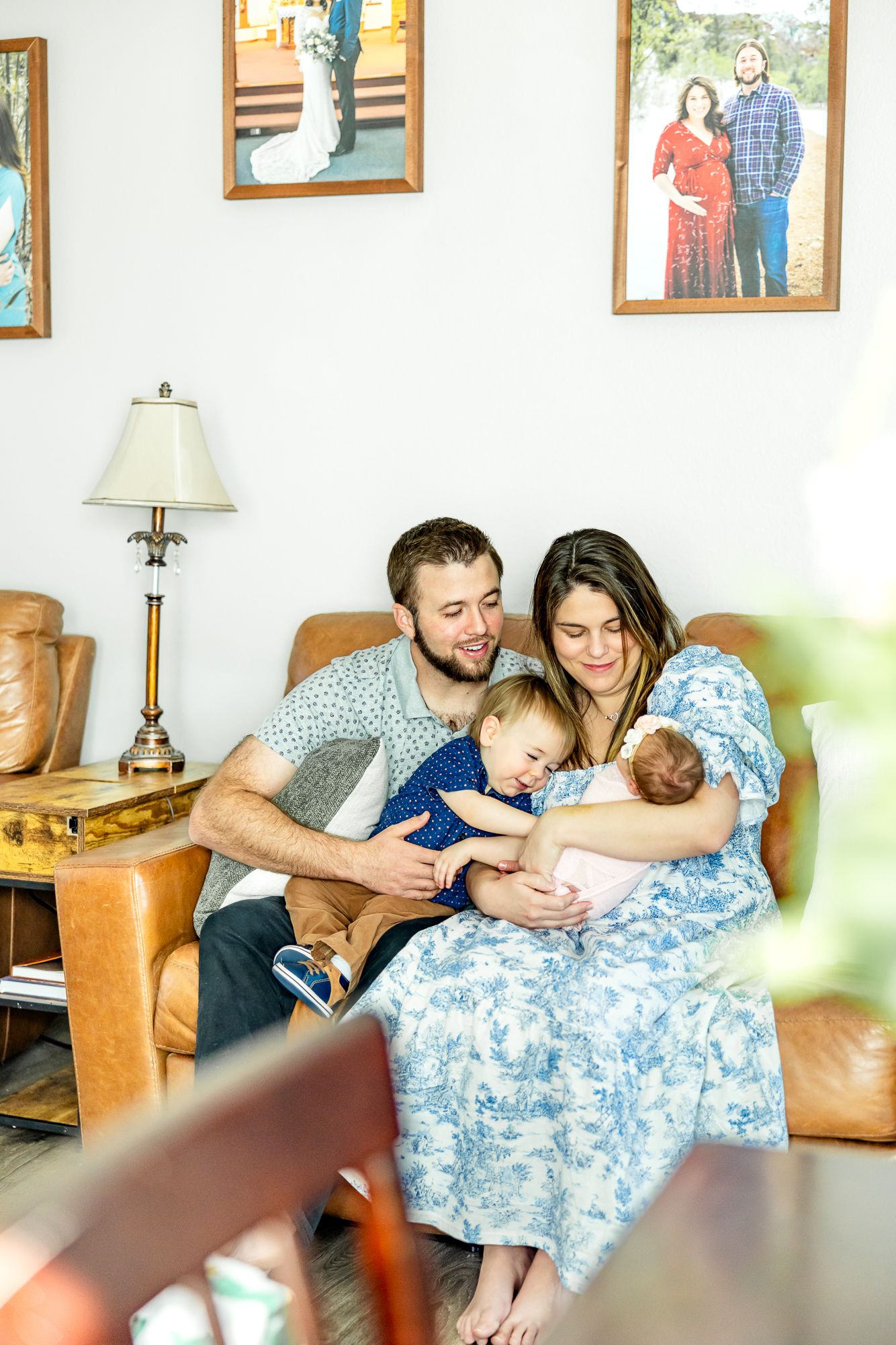 Parents and toddler son smile at new baby girl in mom's arms during lifestyle newborn photos in Colorado Springs.