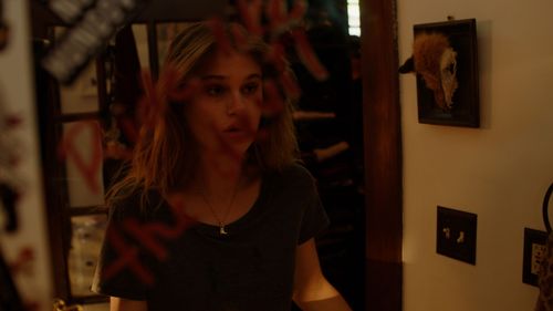 Person gazes intensely in dimly lit interior setting with warm tones.