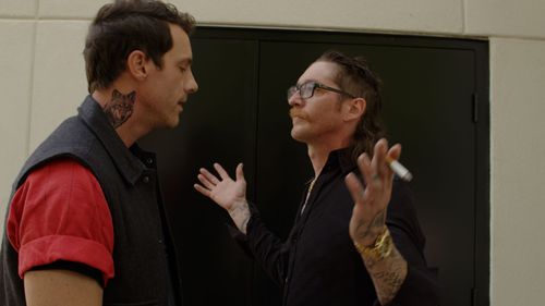 Two people having animated discussion in building hallway.