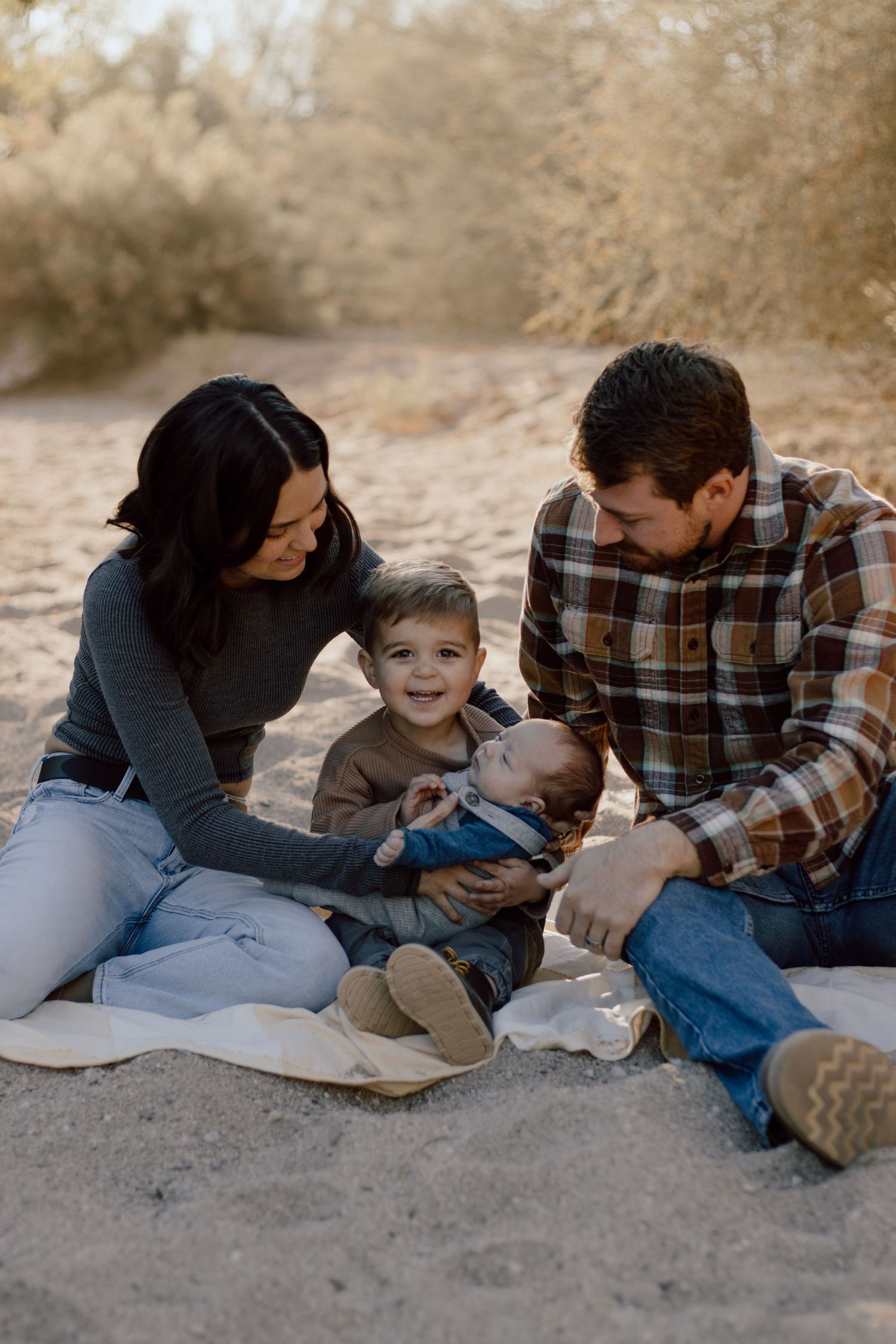 A family sitting together on a blanket in a desert setting during golden hour.