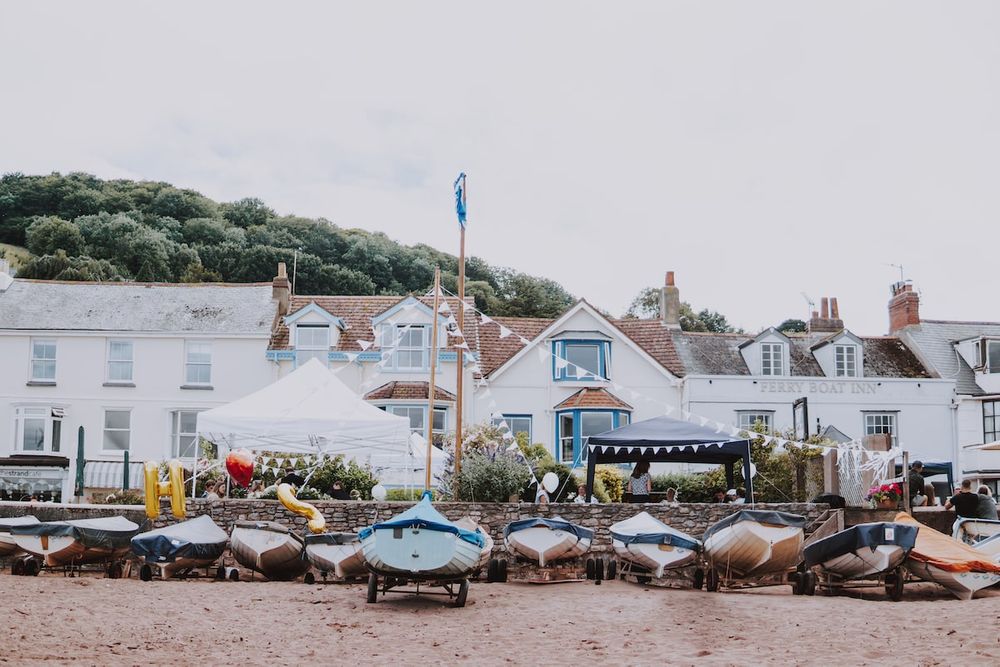 Coastal scene with small boats lined up on a beach near quaint white houses.