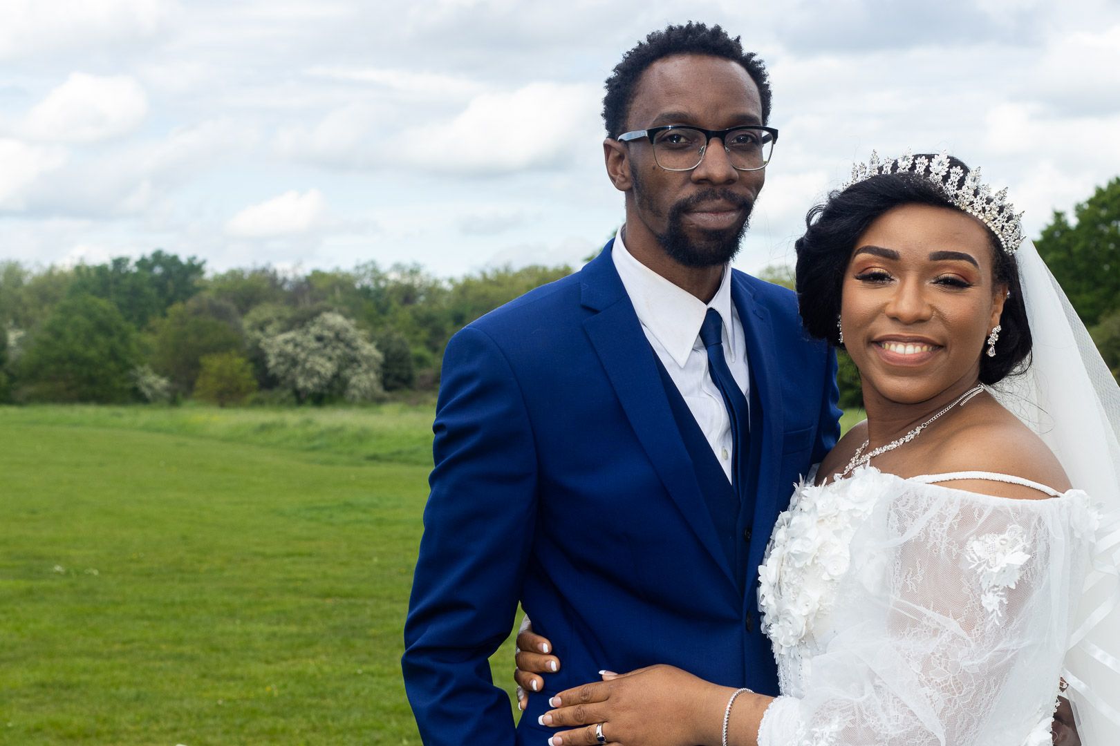 Newlyweds pose together on green lawn during spring wedding celebration.