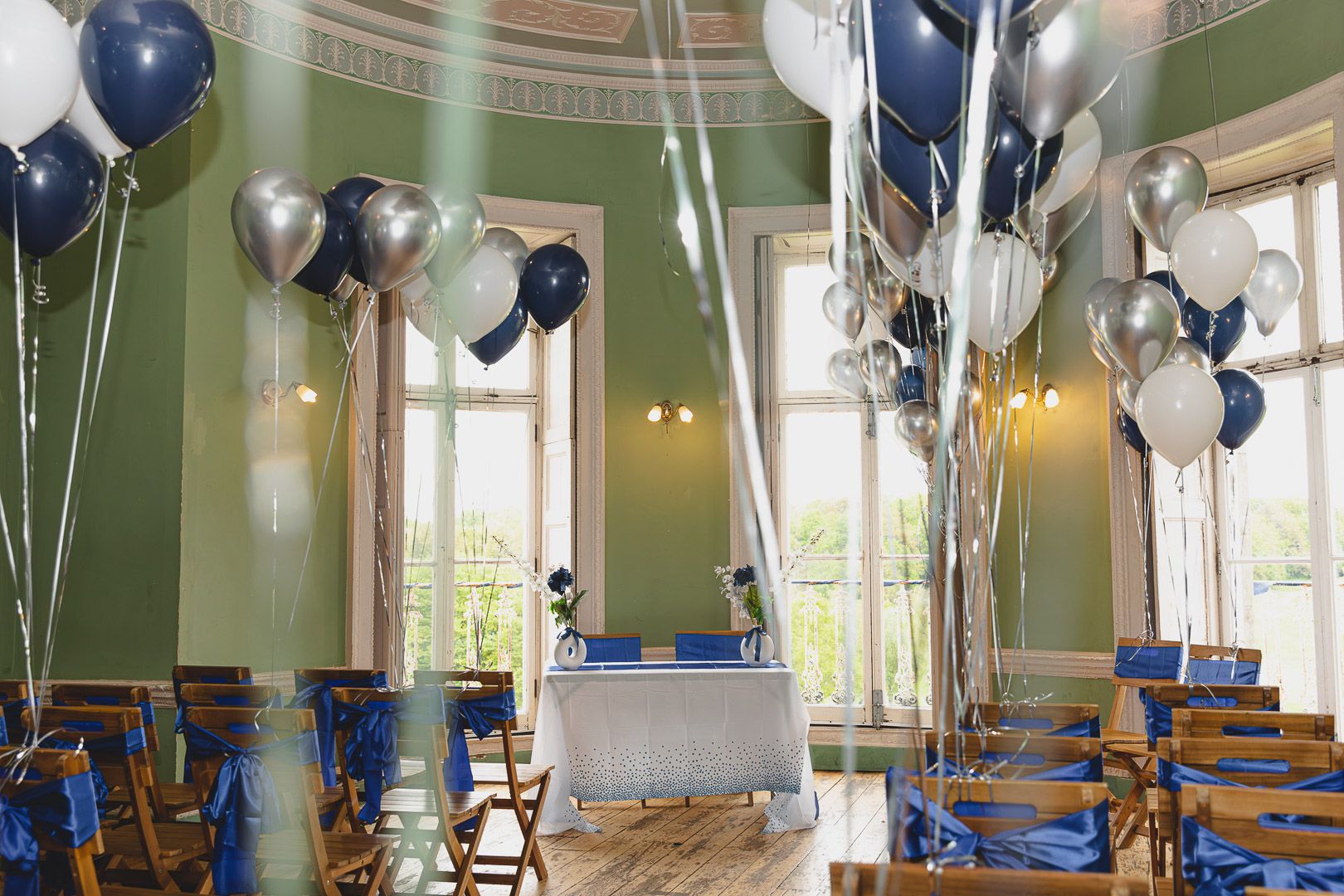 Wedding reception room decorated with blue and silver balloons and elegant table settings.