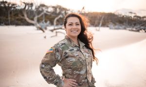 Military service member poses in camouflage uniform during sunset photo session.