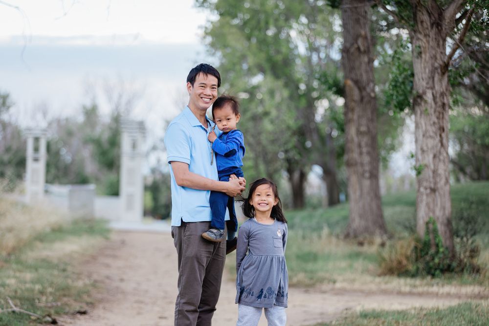Parent and children enjoying time together on a tree-lined path outdoors.