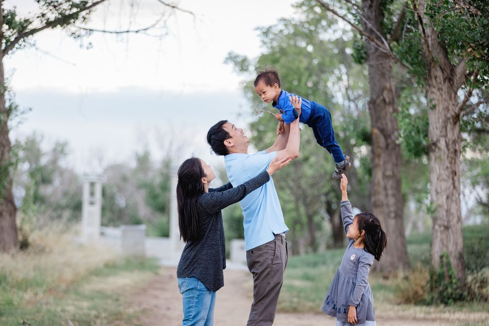 Family playing together on an outdoor path with trees in the background.