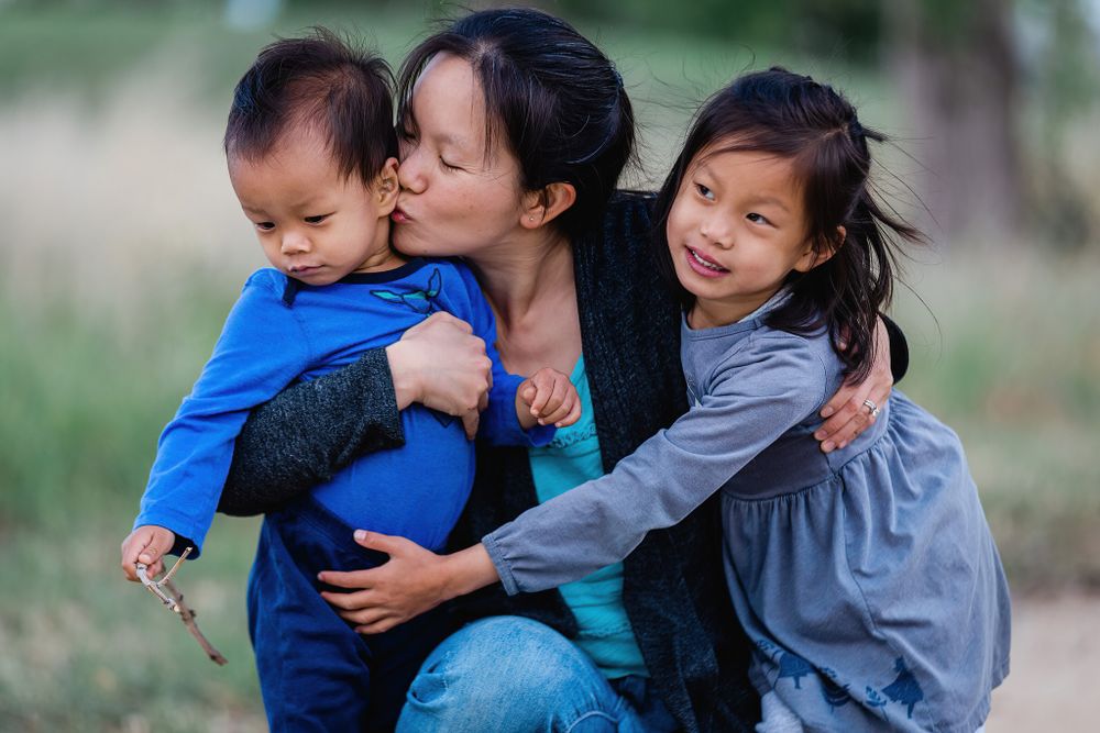 A tender embrace between family members surrounded by nature and greenery.