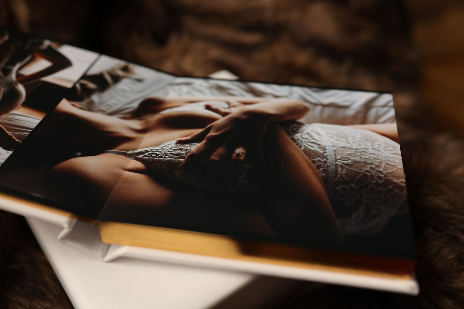 Close-up shot of hands resting on a dark surface with photographs scattered in moody lighting.