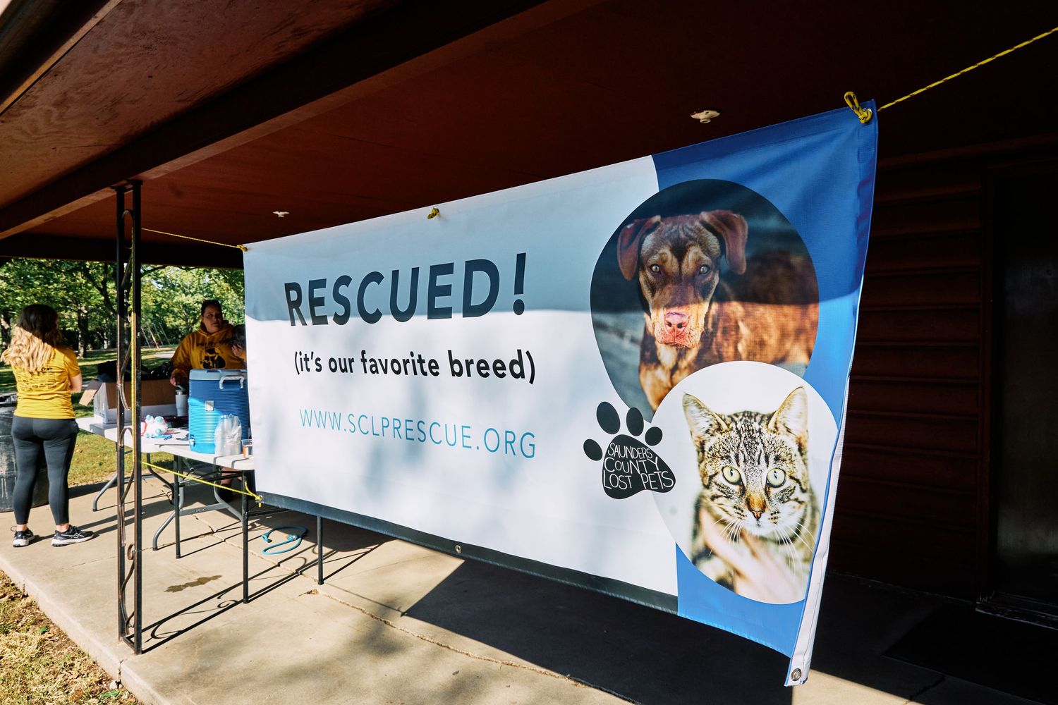 Row of blue banners with pet-related messaging displayed at an outdoor event.