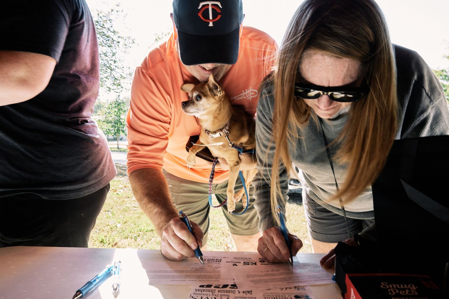 Group wearing orange and black clothing gathered together in an outdoor setting.