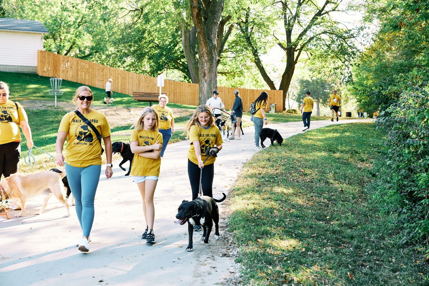 Participants walking with their pets during an outdoor event in a park setting.