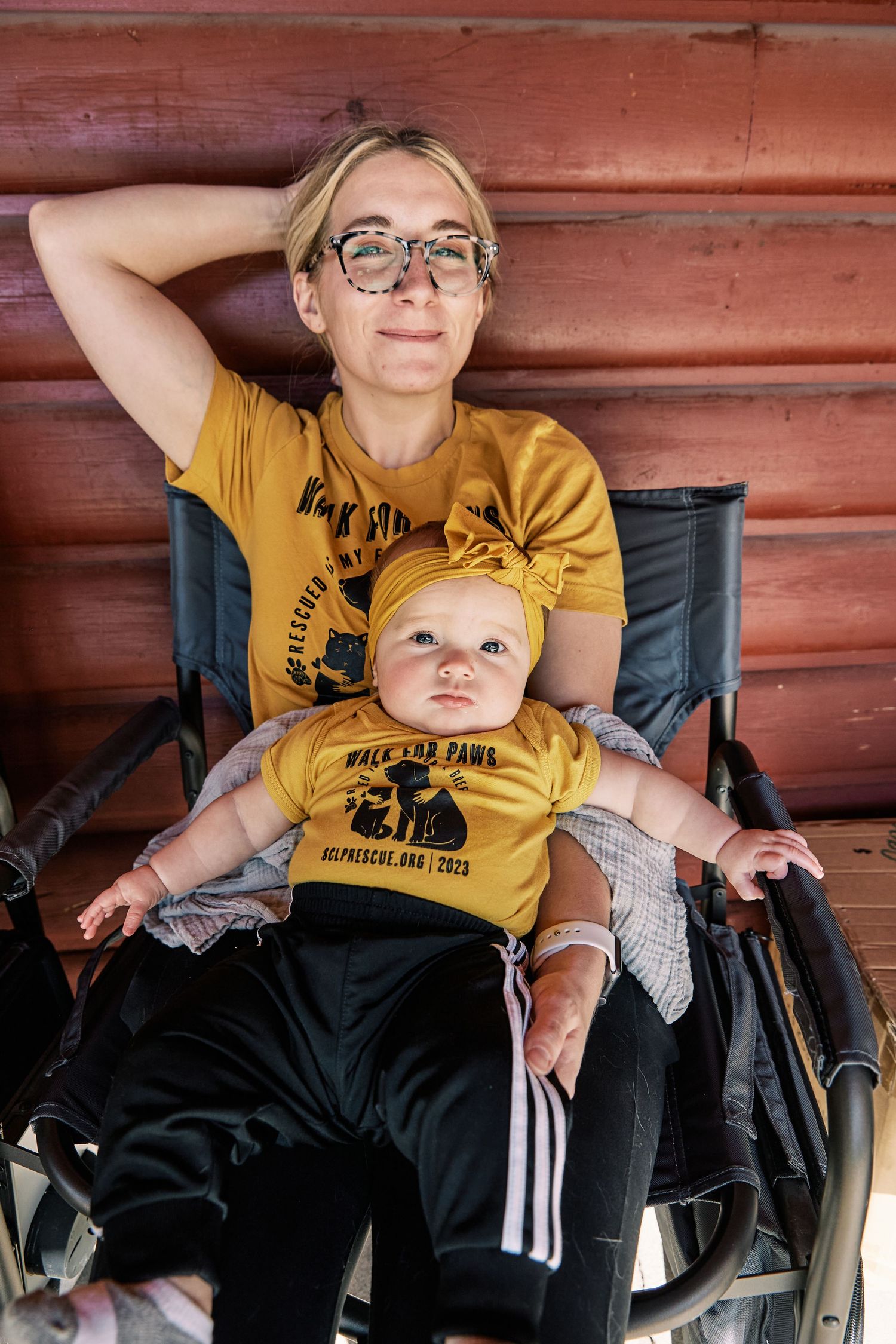 Relaxed scene with matching yellow shirts against a red wooden wall background.