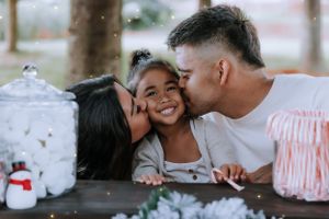 A loving family shares tender moments on a red blanket during a Christmas-themed photo session.