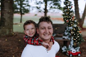 A joyful family moment captured during a Christmas-themed outdoor photo session.