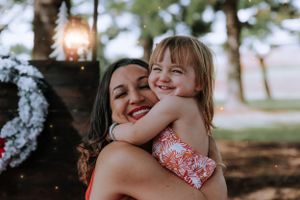 Joyful holiday portraits taken outdoors with pine trees in the background.