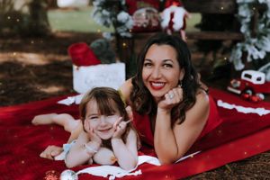 Playful holiday photo session on a red blanket with Christmas decorations.