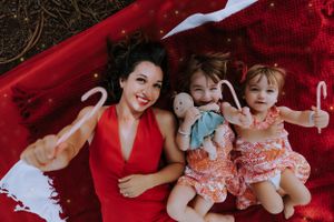 Holiday family photoshoot with Christmas decorations and red blanket outdoors.