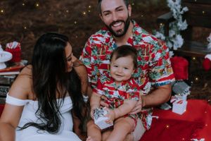 A family in festive attire shares a joyful moment during Christmas photos outdoors.