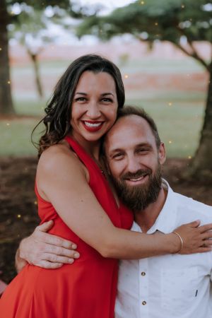 A couple in red and white outfits share loving embraces in a series of outdoor photos.
