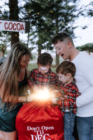 A family reveals a 'Don't Open Till Dec 25' message during their holiday photo session.