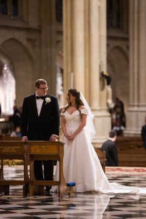 Bride and groom stand together at the altar inside a grand cathedral during their wedding ceremony.