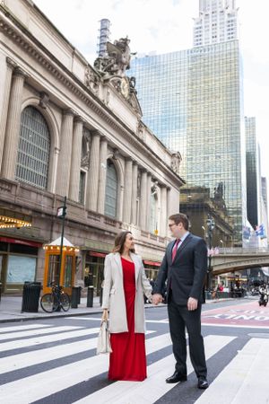 Couple holding hands on zebra crossing outside Grand Central Terminal in New York City.