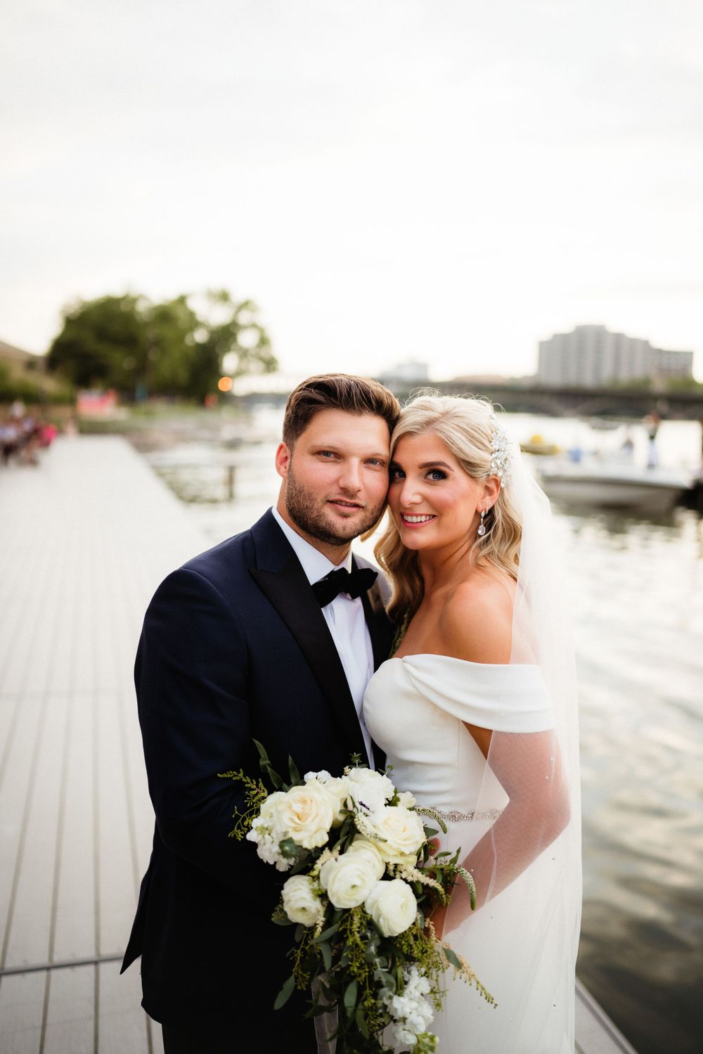 A waterfront wedding portrait with marina and water in background.