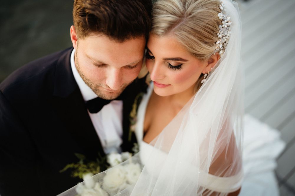 An intimate wedding portrait featuring a white bridal gown and black tuxedo.