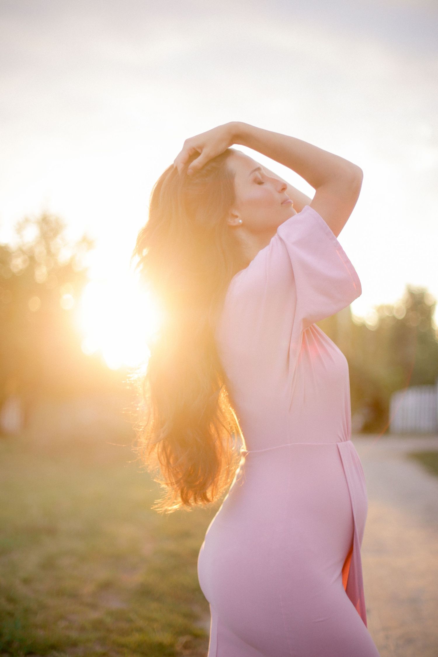Graceful pose in pink dress against golden sunset light.