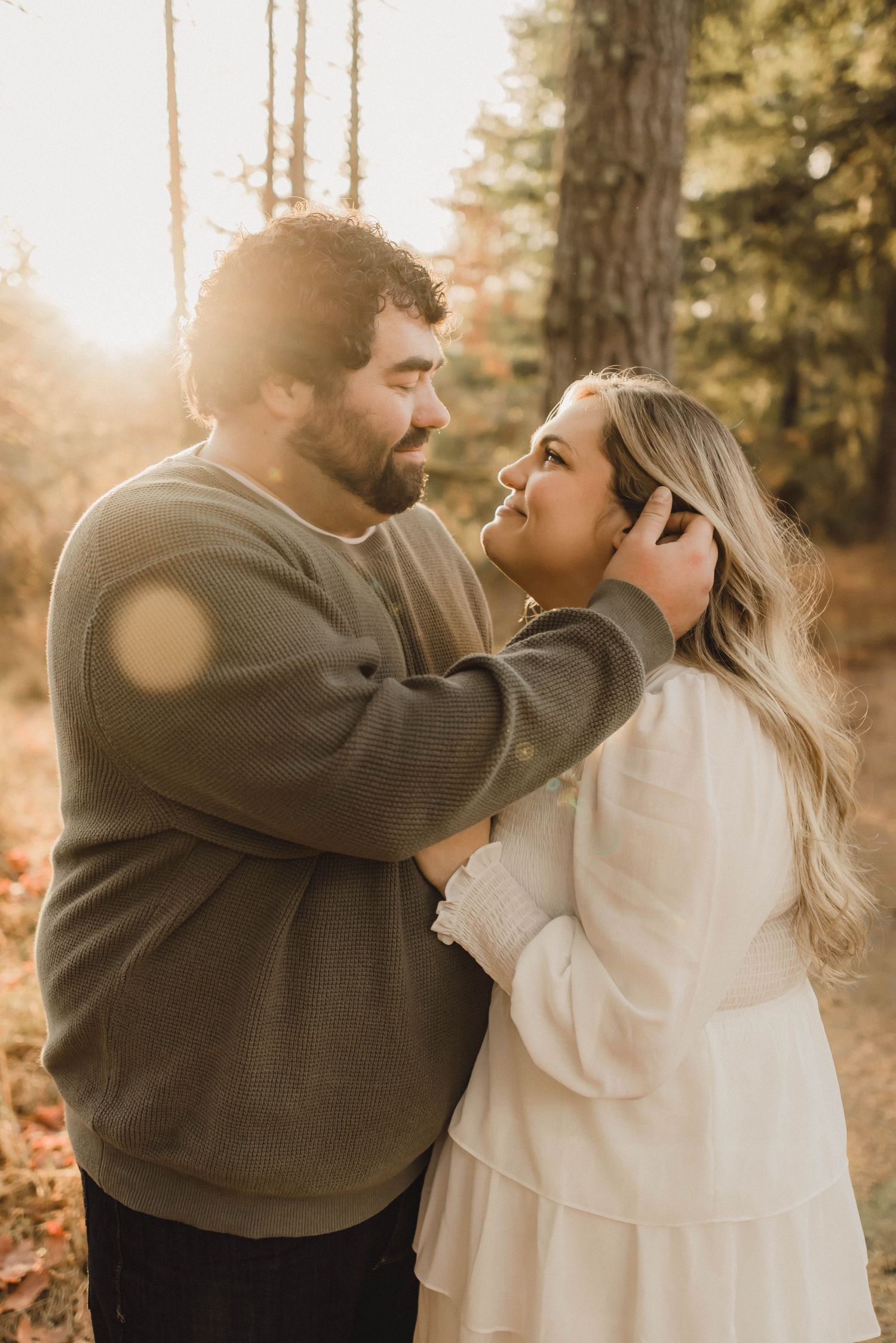 Couple embracing in golden hour sunlight in a serene forest.