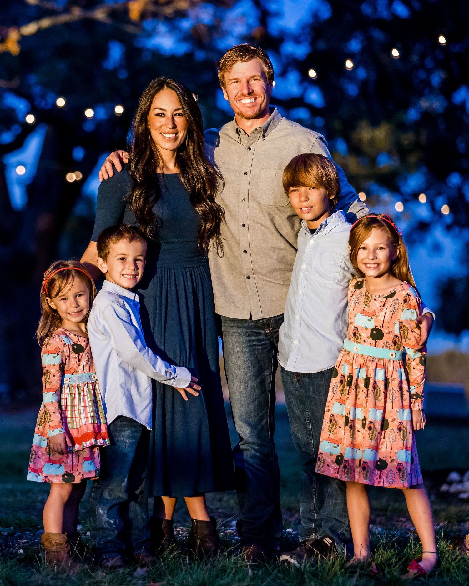 Family portrait outdoors at dusk with blue lighting and children in coordinated outfits.