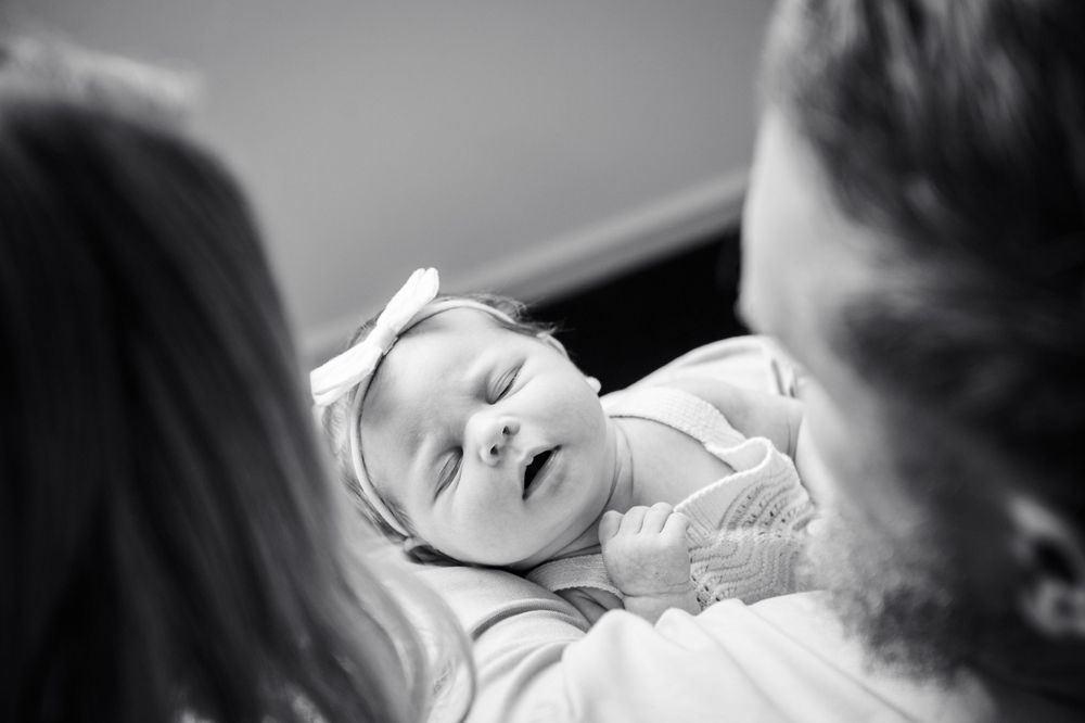 Peaceful newborn baby with white bow sleeps while being held.
Altona Family Photographer Melbourne