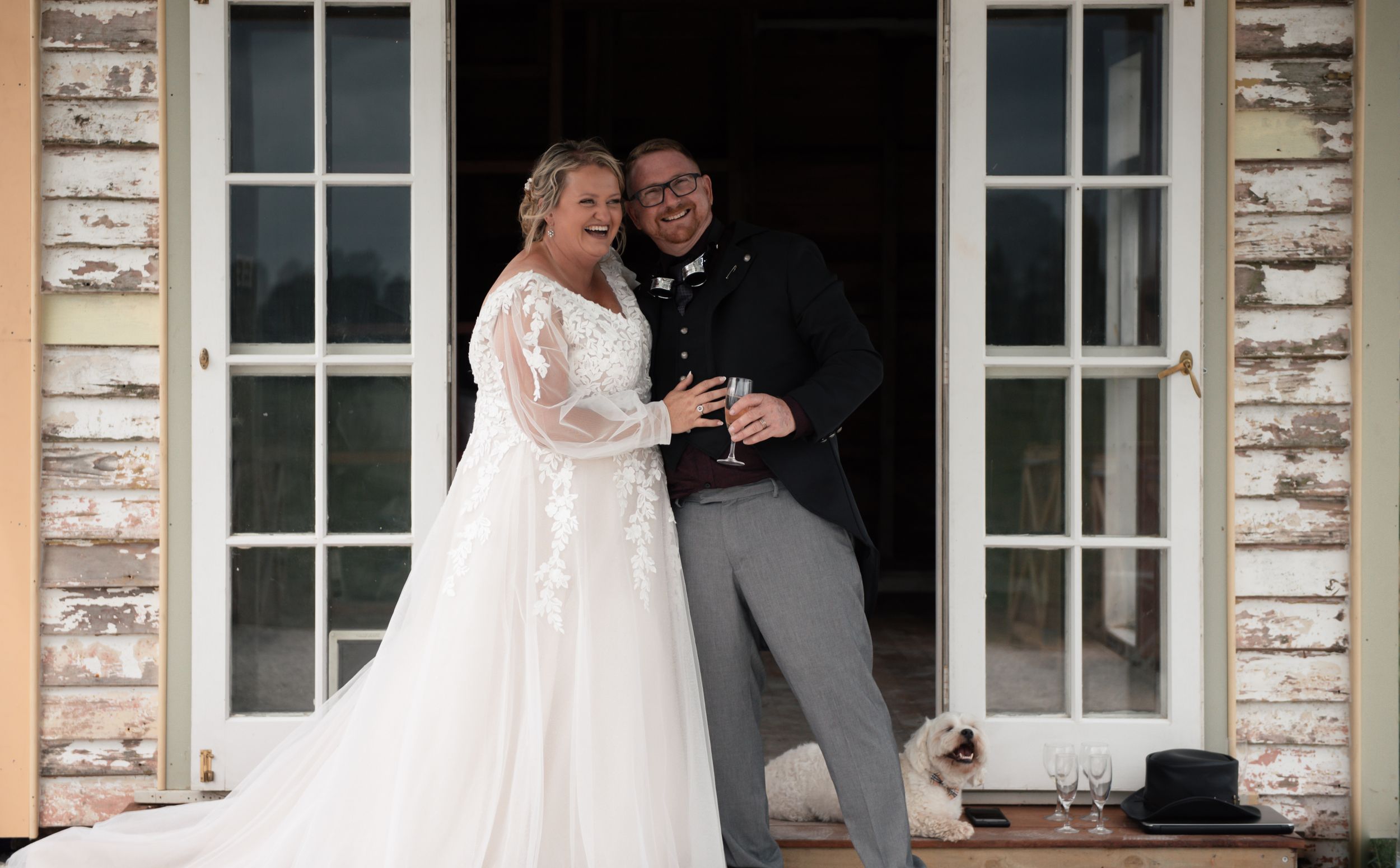 Newlyweds share joyful moment in doorway of stone building.