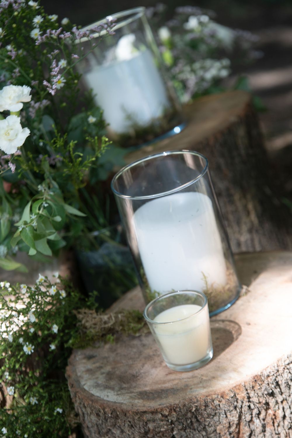 diy wedding decoration candles in jars with babys breath on cut logs along aisle