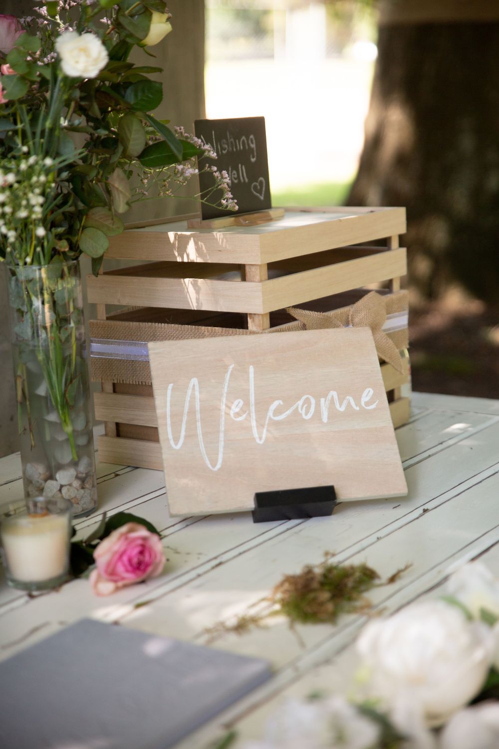diy wedding deocration  wishing well sign on table strewn with fresh flowers in pink and white