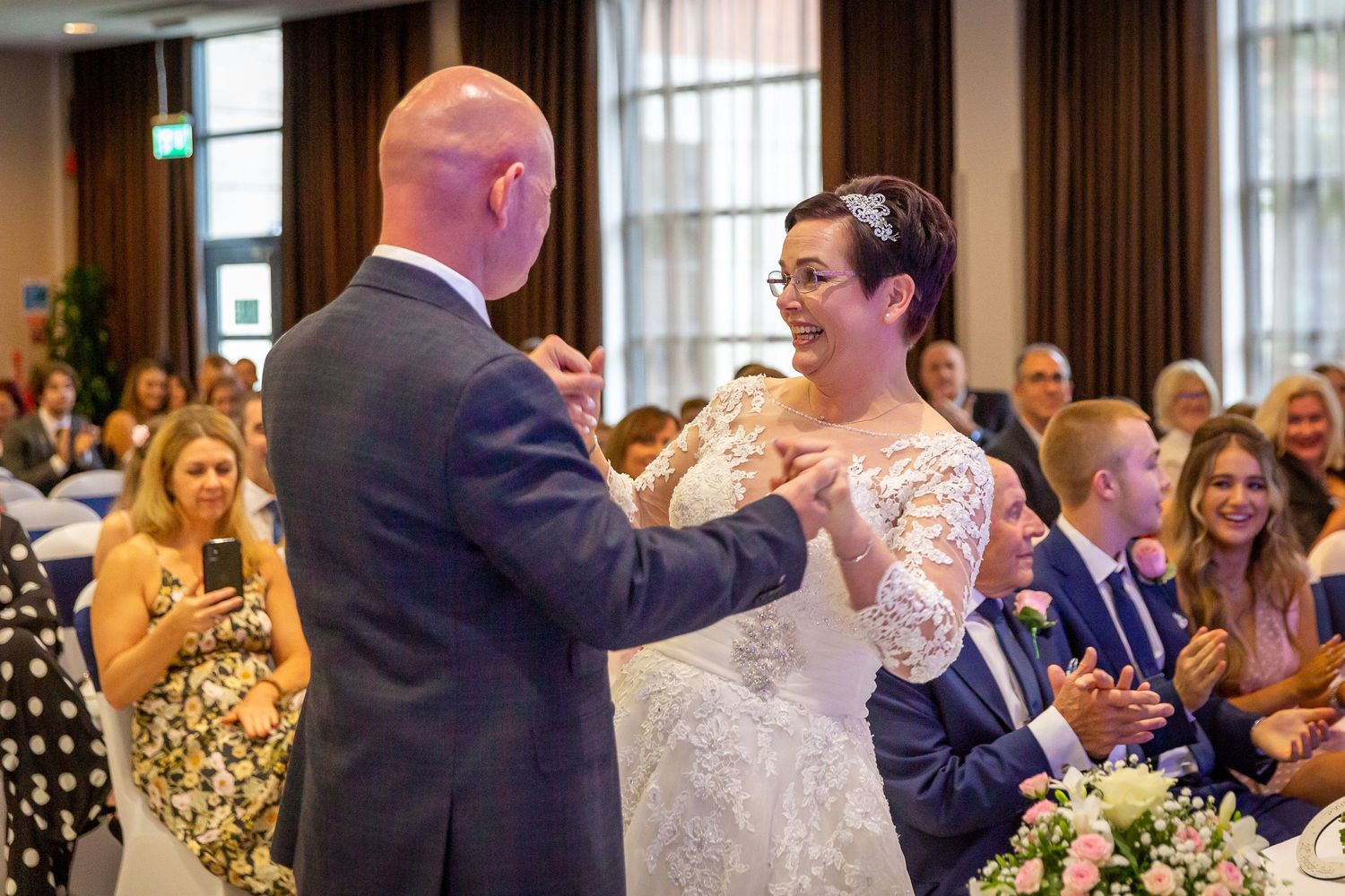 Newlyweds face each other hold hands, arms in the air, smiling during the ceremony. Liverpool wedding photographer.