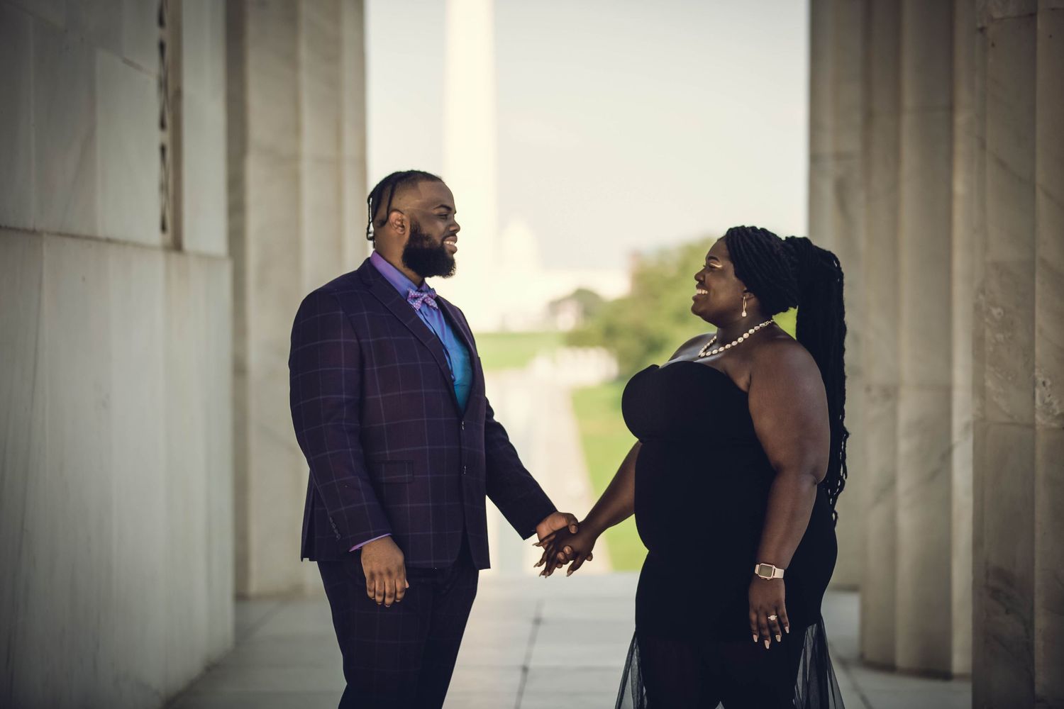An elegant couple holds hands and gazes at each other between marble columns at the Lincoln Memorial.