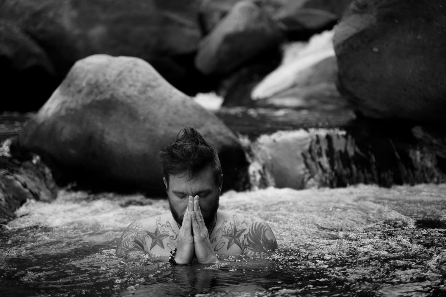 Person relaxing in natural rock pool with hands clasped near face.