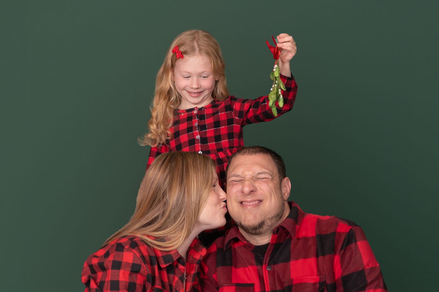 family photo on plain green backdrop with mistletoe in studio on green backdrop clayton new jersey gloucester county