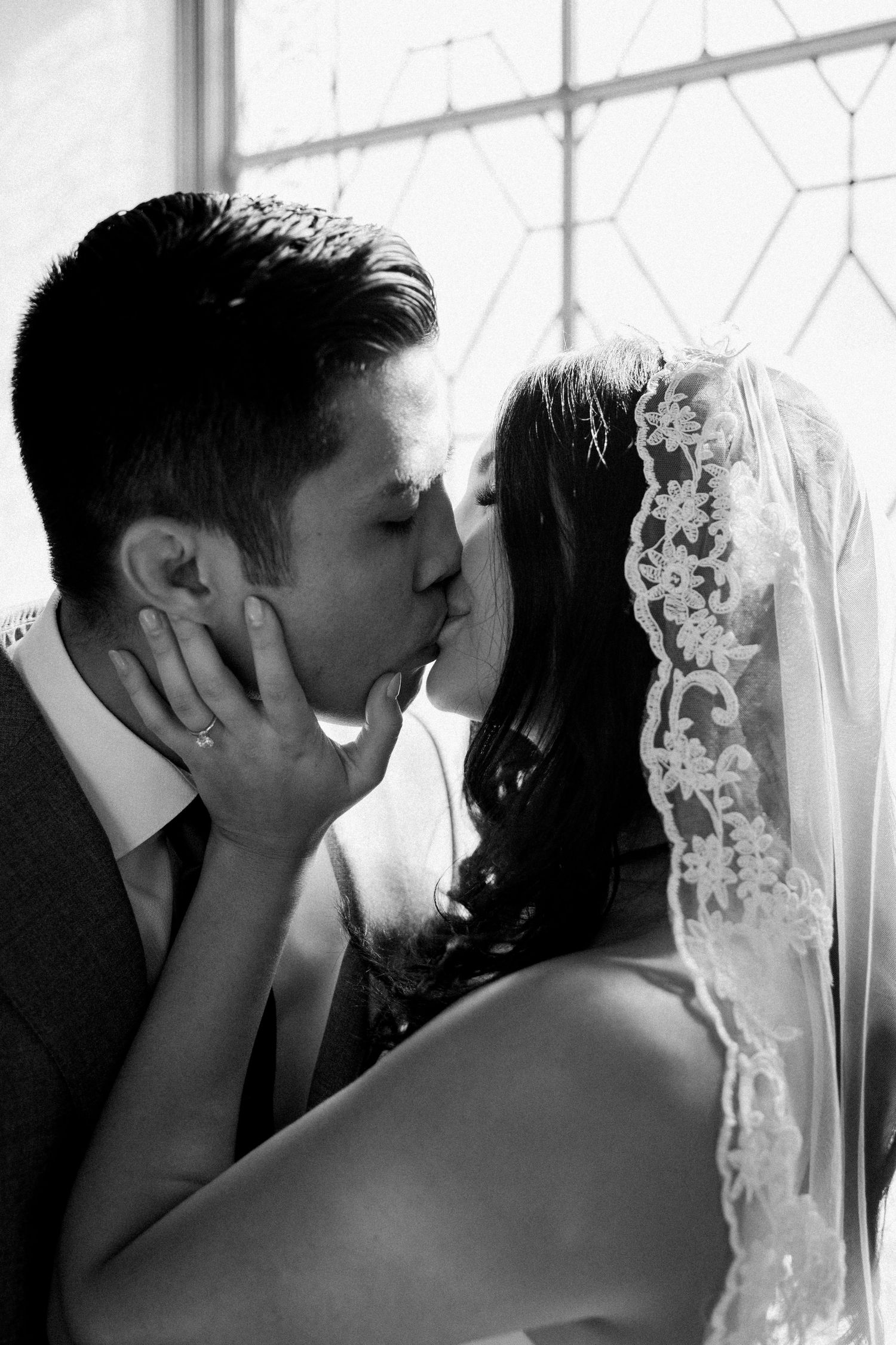 Asian groom and Caucasian bride in short wedding dress kiss after getting married at San Francisco City Hall.